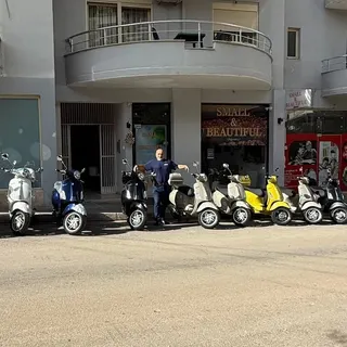 A row of Vespas in front of the Small & Beautiful shop, seen from across the street