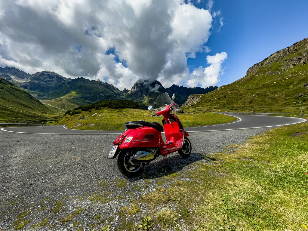 A red Vespa GTS on a mountain road