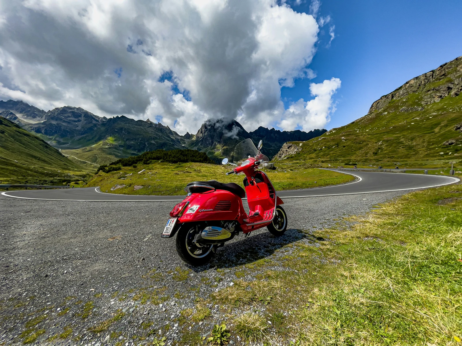 A red Vespa GTS on a mountain road