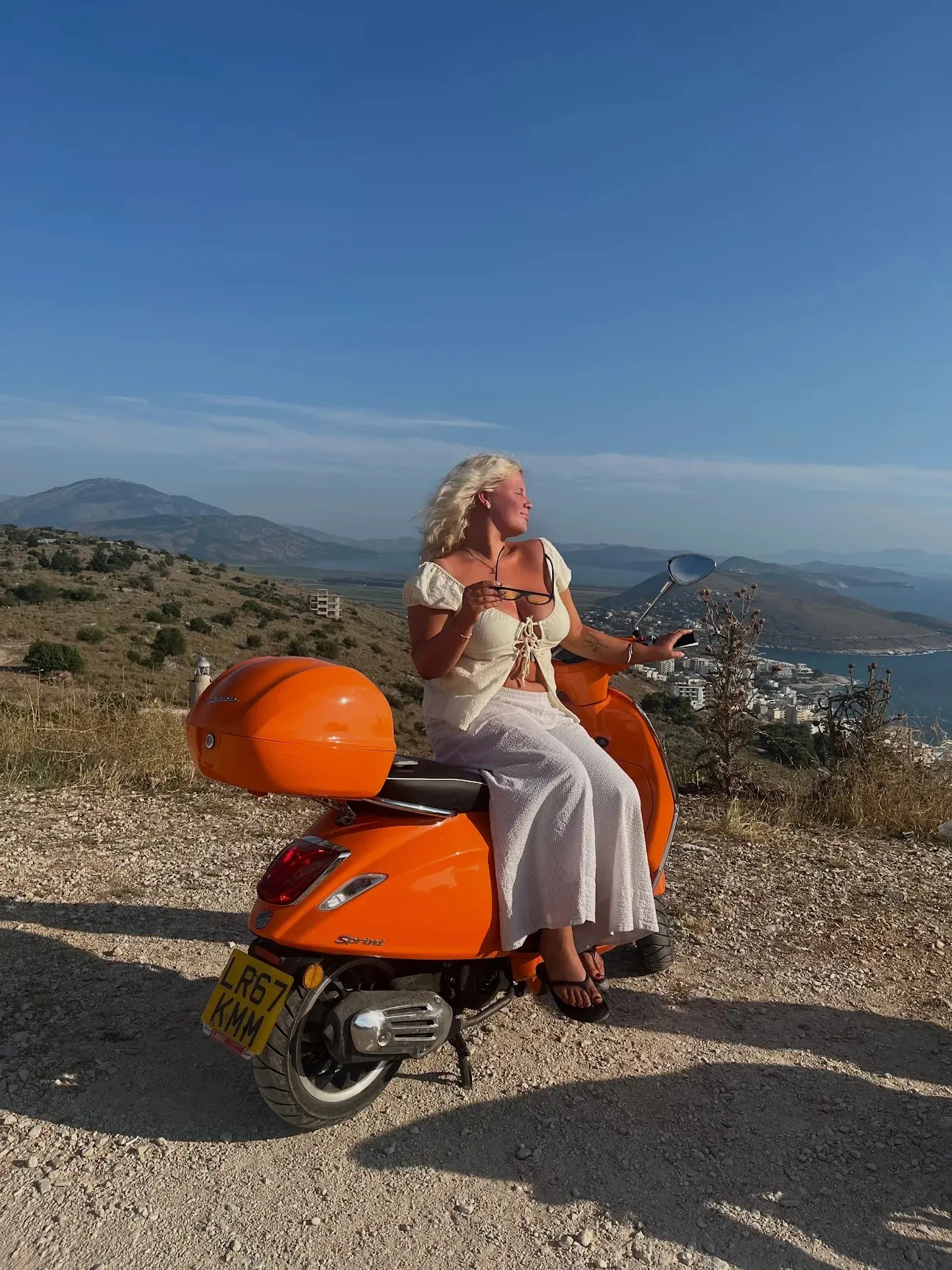 A guest on an orange Vespa at a viewpoint above the coast